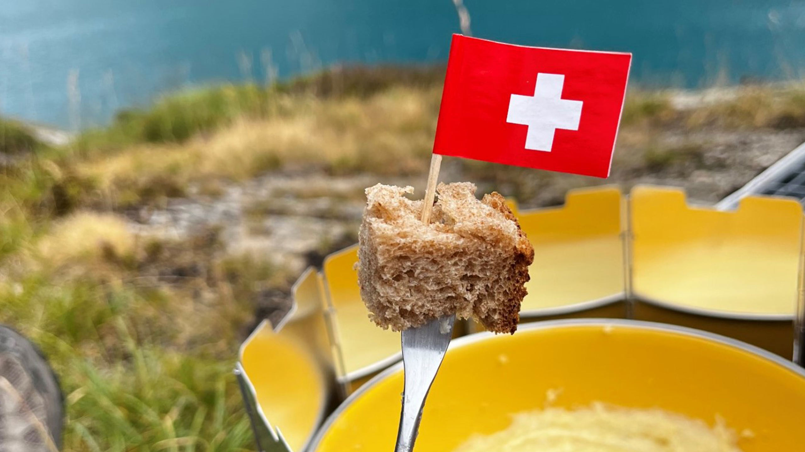 Fondue Gabel mit einem Stück Brot und Zahnstocker-Schweizerfahnen