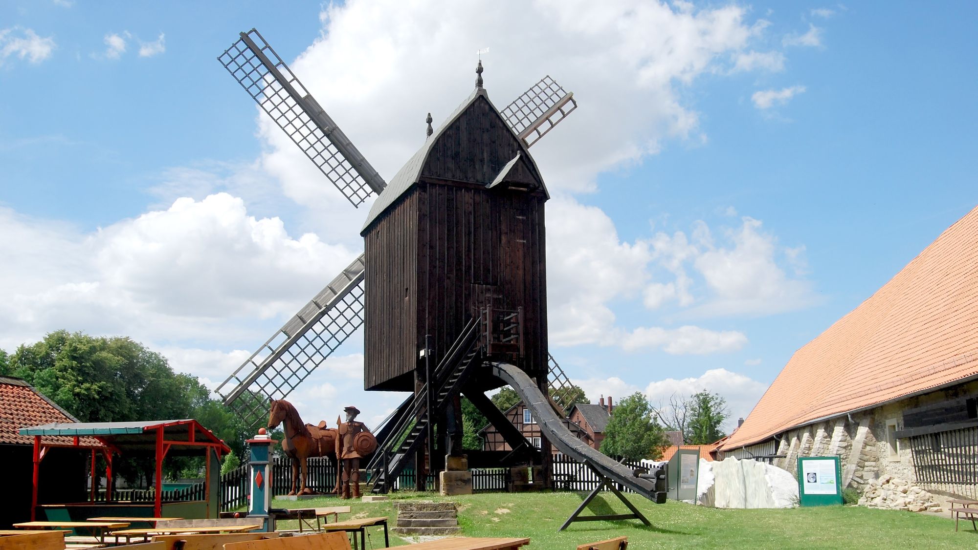 Historische Osterlinder Bockwindmühle aus Holz an einem sonnigen Tag unter blauem Himmel.