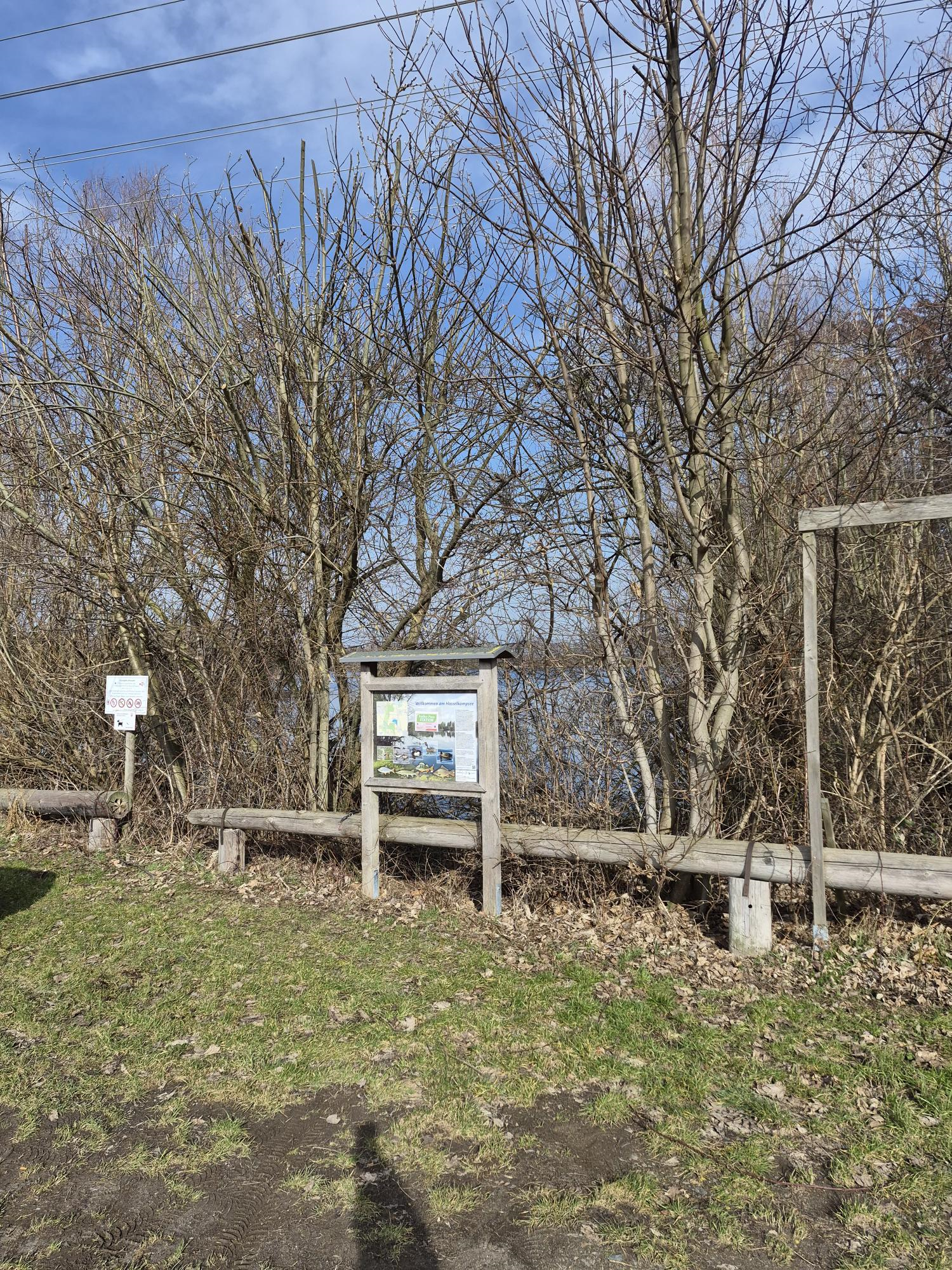 Infotafel am Naturlehrpfad Vechelde zwischen Bäumen und Wiesenrand.